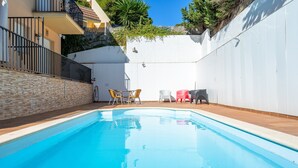 Ein Schwimmbecken mit Fliesen, einer weißen Wand und einer Ziegelwand mit Metallgeländer.