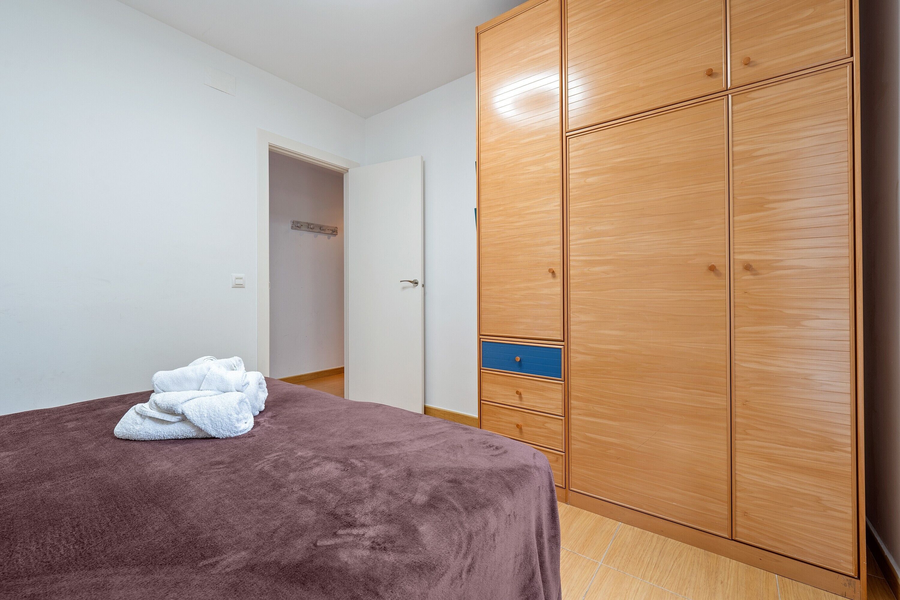 Une chambre à coucher avec un lit, une armoire en bois et une porte donnant sur une autre pièce.