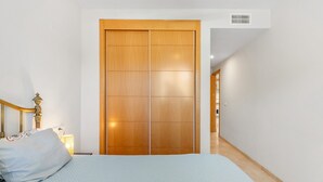 A bedroom with a bed, a wooden wardrobe, and a hallway. - Benalmádena-Arenal Golf Apartment with Shared Pool, Wi-Fi, and Air Conditioning (Benalmádena)