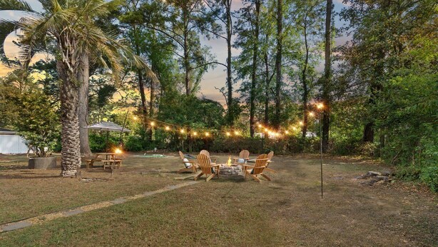 Un jardin avec un foyer, des chaises et des guirlandes lumineuses.