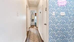 Un couloir avec un papier peint à motifs, un panneau lumineux au néon et un tapis à motifs.