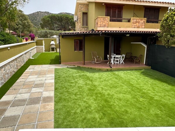 A house with a patio, a lawn, and a stone wall.