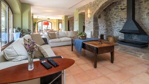 A cozy living room with a stone fireplace, a sofa, a coffee table, and a vase with flowers. - Rural House 'Mas Darovie' with Mountain View, Wi-Fi and Air Conditioning (Foixá)