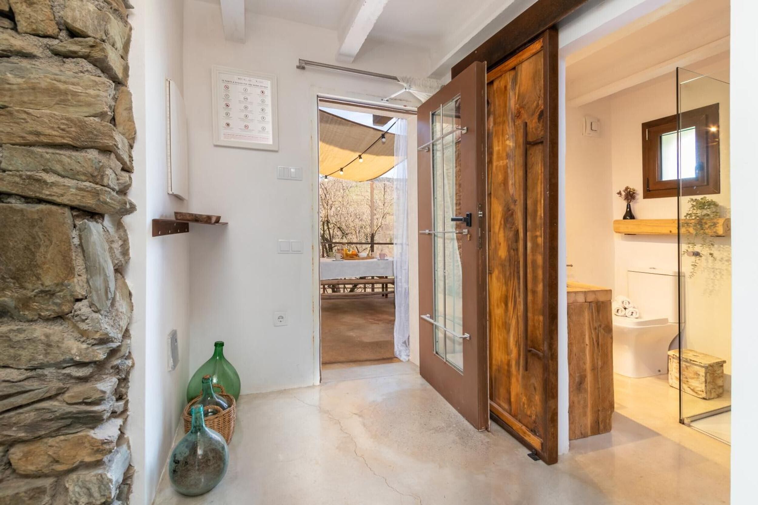 Un pasillo con pared de piedra, puerta de madera y cabina de ducha de vidrio.