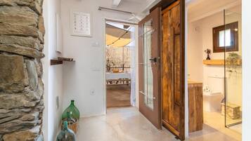Un pasillo con pared de piedra, puerta de madera y cabina de ducha de vidrio.