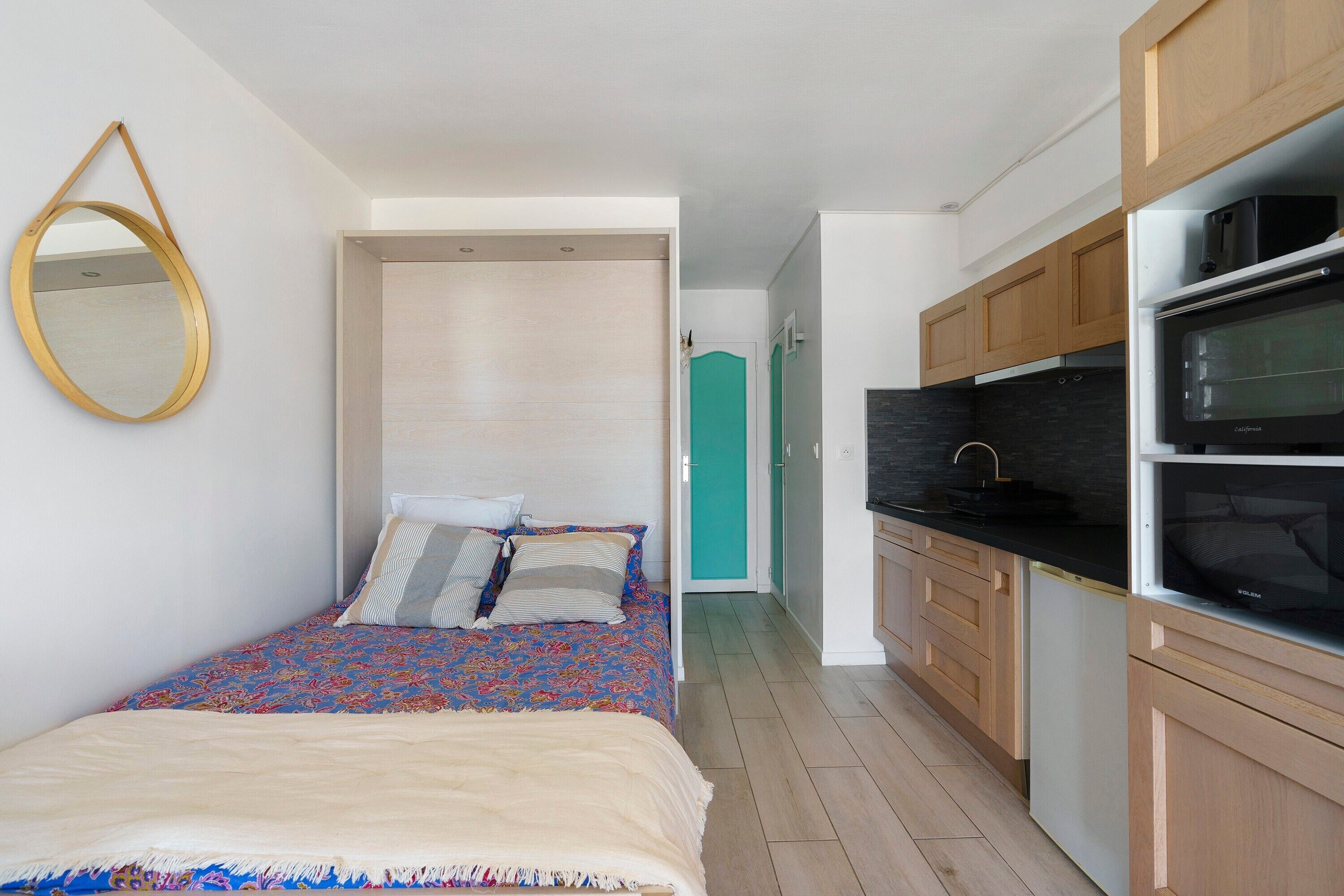 Une chambre à coucher de taille réduite, comprenant un lit, une table de chevet et un miroir.