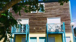 A building with two blue doors, a wooden facade, and a balcony with a blue railing.