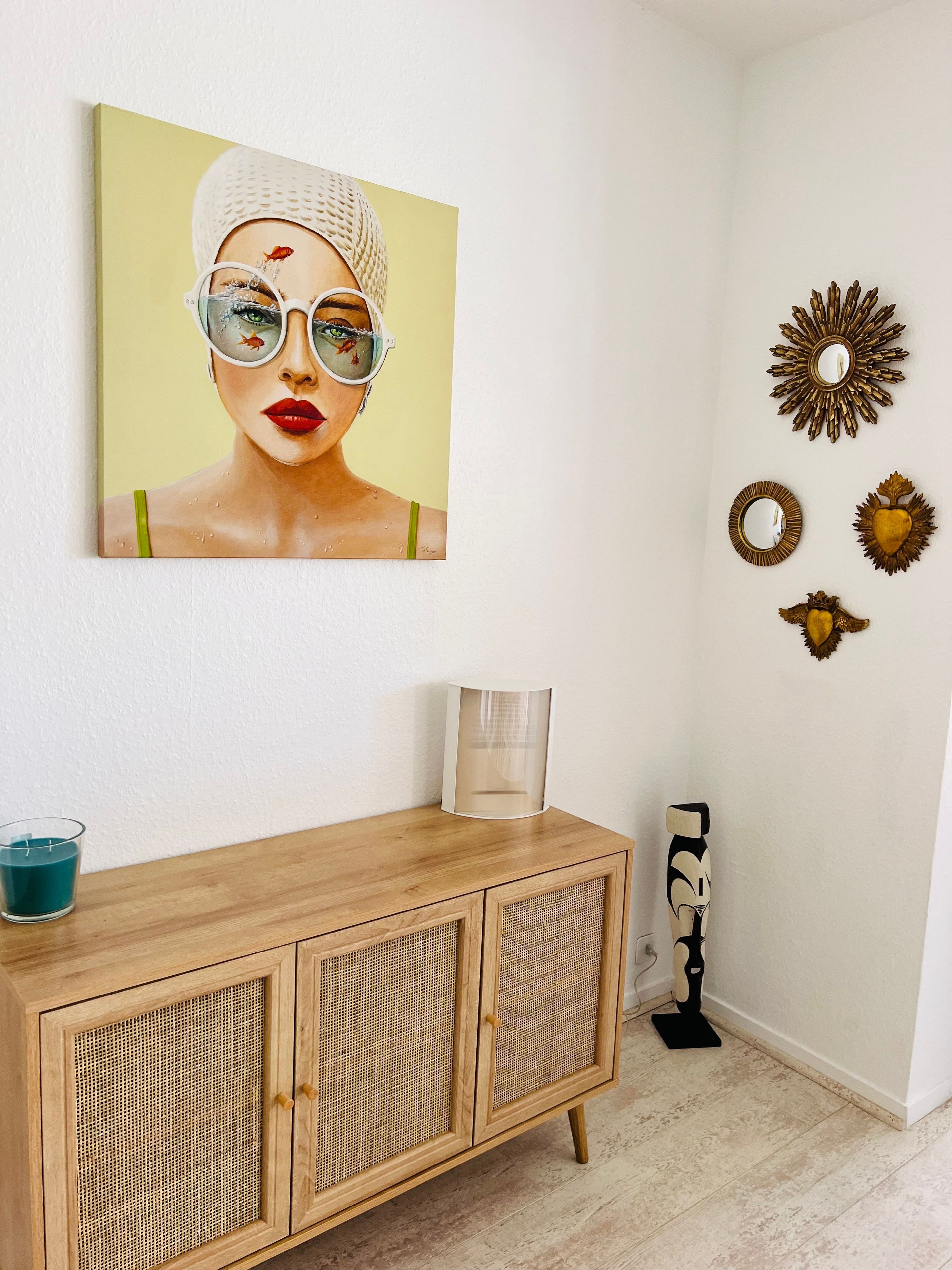 Una habitación con un armario de madera, una obra de arte enmarcada y espejos decorativos en la pared.