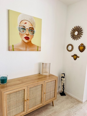 A room with a wooden cabinet, a framed artwork, and decorative wall mirrors.