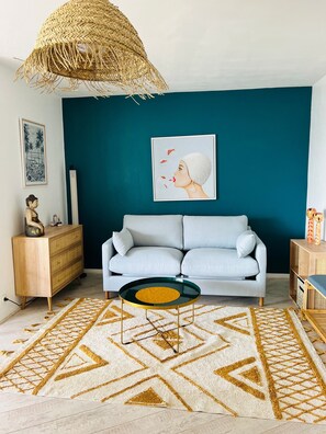 A living room with a sofa, a coffee table, a decorative basket, and a framed picture on the wall.