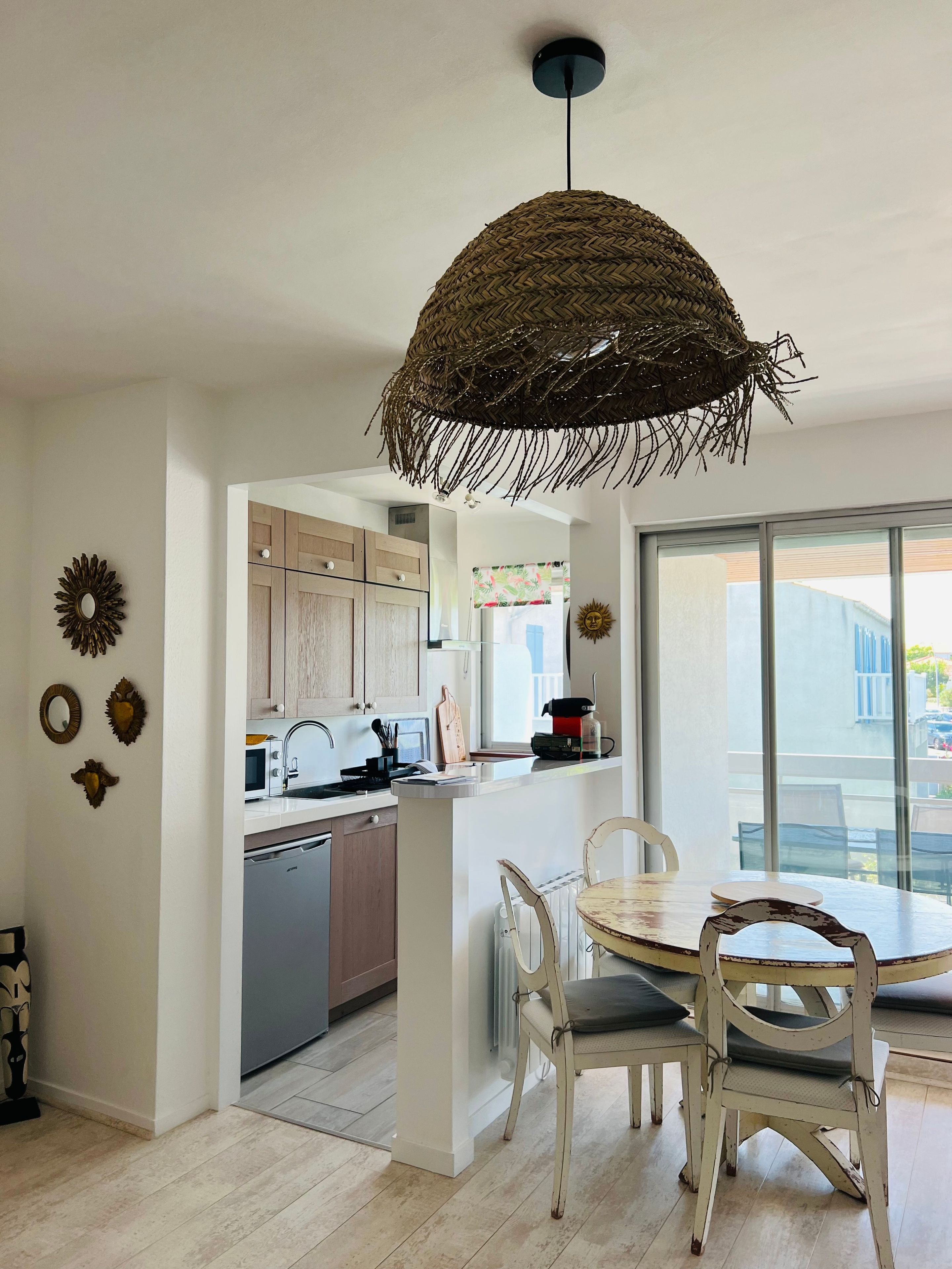Una cocina moderna con armarios blancos, una isla central y un comedor con sillas blancas.