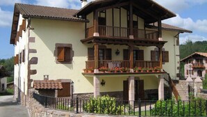 A two-story building with a balcony, stone wall, and potted plants. - Country House 'Matxingonea 1' with Mountain View, Private Garden and Wi-Fi (Leorlas)