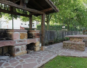 Un espace barbecue extérieur doté de foyers en pierre et d’un coin salon abrité.