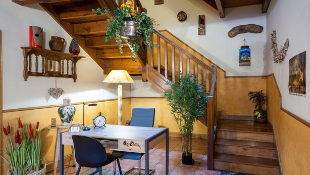 A wooden staircase with a hanging plant, a dining table with chairs, and a wall-mounted shelf with decorative items. - Country House 'Matxingonea 1' with Mountain View, Private Garden and Wi-Fi (Leorlas)