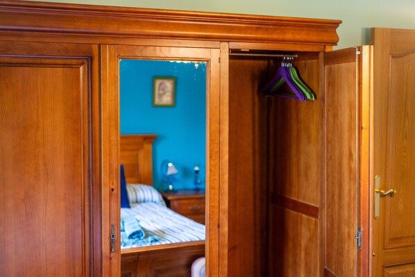 A wooden wardrobe with a mirror, a bed with striped bedding, and a blue wall with a picture. - Country House 'Matxingonea 1' with Mountain View, Private Garden and Wi-Fi (Leorlas)