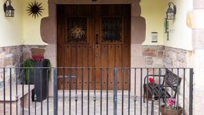 A wooden double door with a number '18' above it, a stone wall, a metal fence, and two potted plants with flowers. - Country House 'Matxingonea 1' with Mountain View, Private Garden and Wi-Fi (Leorlas)