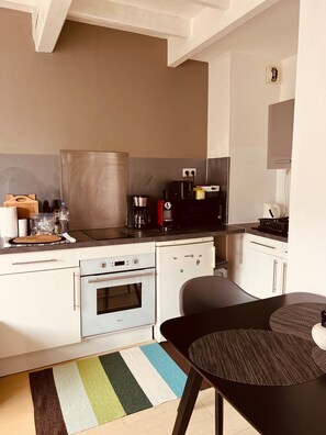 Una cocina moderna con armarios blancos, una campana extractora de acero inoxidable, una cafetera y un microondas.