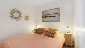 Un dormitorio con cama, dos lámparas de noche, un cuadro colgado en la pared y dos adornos murales.