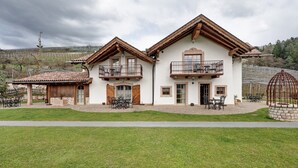 A two-story chalet with balconies, a patio area, and a view of a vineyard. - Apartment 'Red' with Mountain View, Shared Garden and Wi-Fi (Predaia)