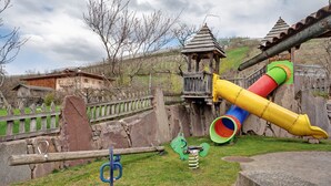 A playground with a slide, swings, and a wooden structure. - Apartment 'Red' with Mountain View, Shared Garden and Wi-Fi (Predaia)