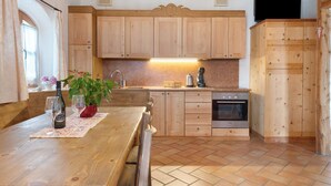 A kitchen with wooden cabinets, a wooden table, a sink, and a stove. - Apartment 'Red' with Mountain View, Shared Garden and Wi-Fi (Predaia)