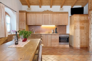A kitchen with wooden cabinets, a wooden table, a sink, and a stove.