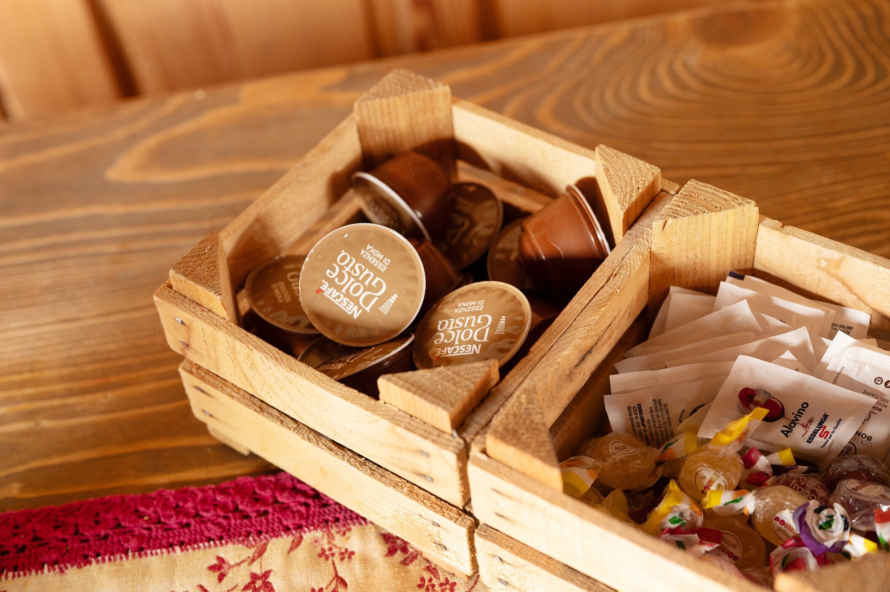 Una cassa di legno piena di diverse tavolette di cioccolato e caramelle confezionate.