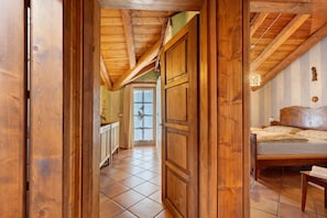 A wooden interior with a bed, a window, and a door.