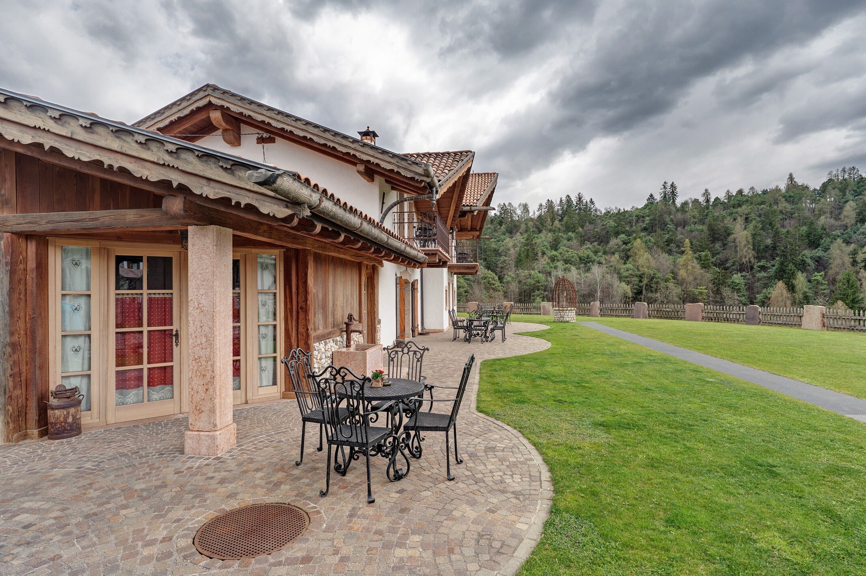A traditional building with a patio, outdoor seating, and a view of a forested hillside.