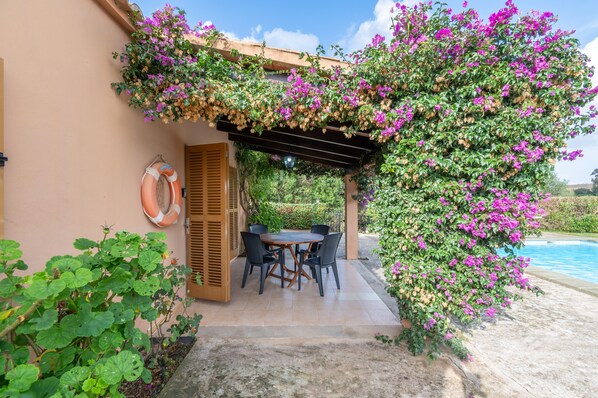Une terrasse avec une table et des chaises, une bouée de sauvetage et une piscine.