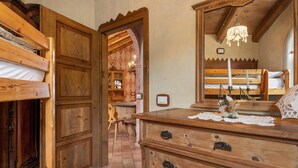 Een houten kamer met stapelbedden, een dressoir en een kroonluchter.