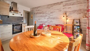 Eine moderne Küche mit Holzschränken, einem Einbauofen und einem Essbereich mit einem runden Holztisch.