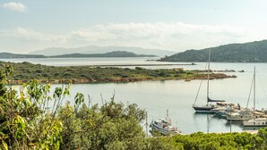A marina with boats docked, surrounded by greenery and hills in the background.