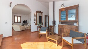 A spacious living area with a sofa, chairs, a wooden cabinet, and a television.