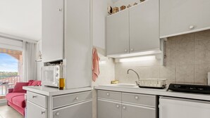Une cuisine moderne avec des meubles blancs, un four à micro-ondes, une bouilloire et une machine à café.