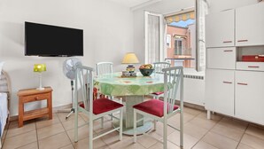 Un espace repas comprenant une table, des chaises, une lampe, un ventilateur et un téléviseur.