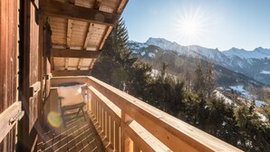 A wooden balcony with a view of snow-covered mountains and a clear sky. - Chalet 'Velajule', private shuttle at the slopes, private jacuzzi & shared pool (Manigod)