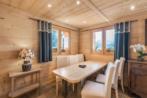 Une pièce aux murs lambrés, comprenant une table à manger, des chaises, une petite table avec une lampe et un buffet.