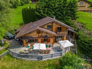 Un chalet en bois doté d’un balcon, d’un espace salon extérieur et d’une terrasse en pierre.