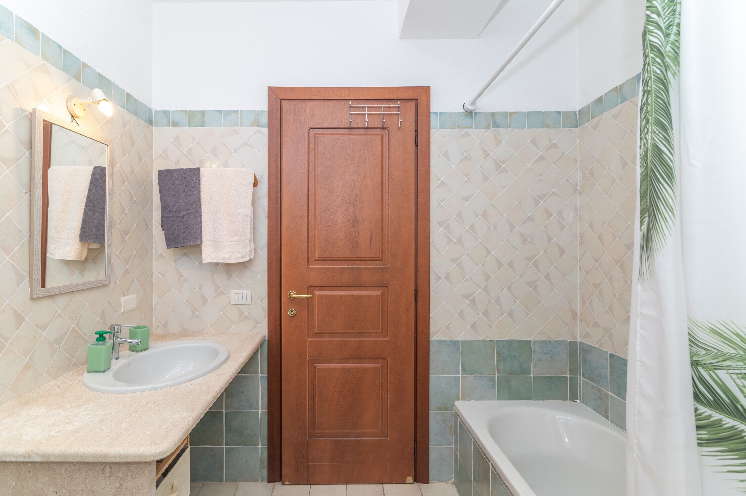 A bathroom with a wooden door, two sinks, a mirror, and a bathtub.