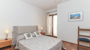 A bedroom with a bed, nightstands, a chair, a picture on the wall, and a view through the window. - Holiday Home 'Le Giare' with Sea View, Wi-Fi, Air Conditioning and Balcony (La Maddalena)
