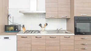 A modern kitchen with a microwave, stove, sink, and cabinets. - Holiday Home 'Le Giare' with Sea View, Wi-Fi, Air Conditioning and Balcony (La Maddalena)