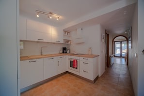 A modern kitchen with white cabinets, a wooden countertop, and a built-in oven.