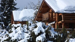 A wooden cabin with a snow-covered roof, surrounded by snow-laden trees. - Chalet Farapreu – Alpine Escape and Absolute Comfort in Manigod (Manigod)