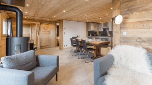 Un intérieur en bois comprenant un coin repas, des canapés, une cheminée et une cuisine.