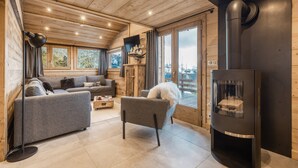 Un salon chaleureux avec une cheminée, un canapé, un fauteuil et un téléviseur.