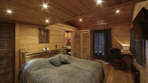 A wooden cabin interior with a bed, a small table, a sink, and a window. - Chalet 'Pesse' with Mountain View, Private Jacuzzi & Shared Pool (Summer Only) (Manigod)