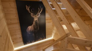 A wooden staircase in a cabin with a poster of a deer on the wall. - Chalet 'Pesse' with Mountain View, Private Jacuzzi & Shared Pool (Summer Only) (Manigod)