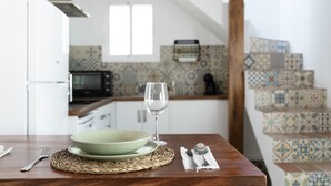 A dining table with a bowl, wine glass, and cutlery, a woven placemat, and a staircase with patterned tiles.