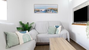 A living room with a sofa, a coffee table, a TV, and a painting on the wall.